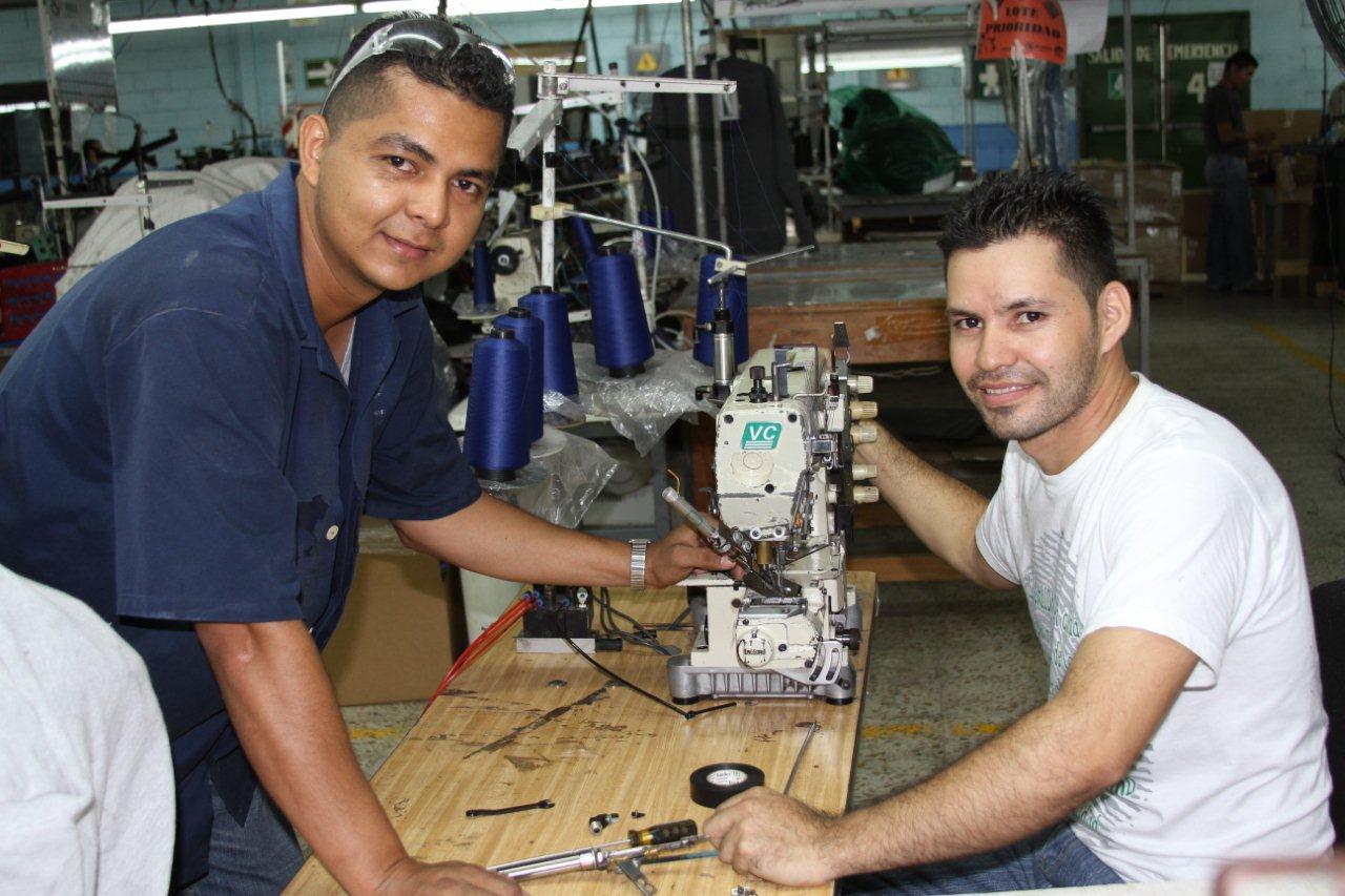 Juan Carlos -de gabacha azul- y Lenín ponen sus conocimientos para contribuir al ahorro en Génesis Apparel.