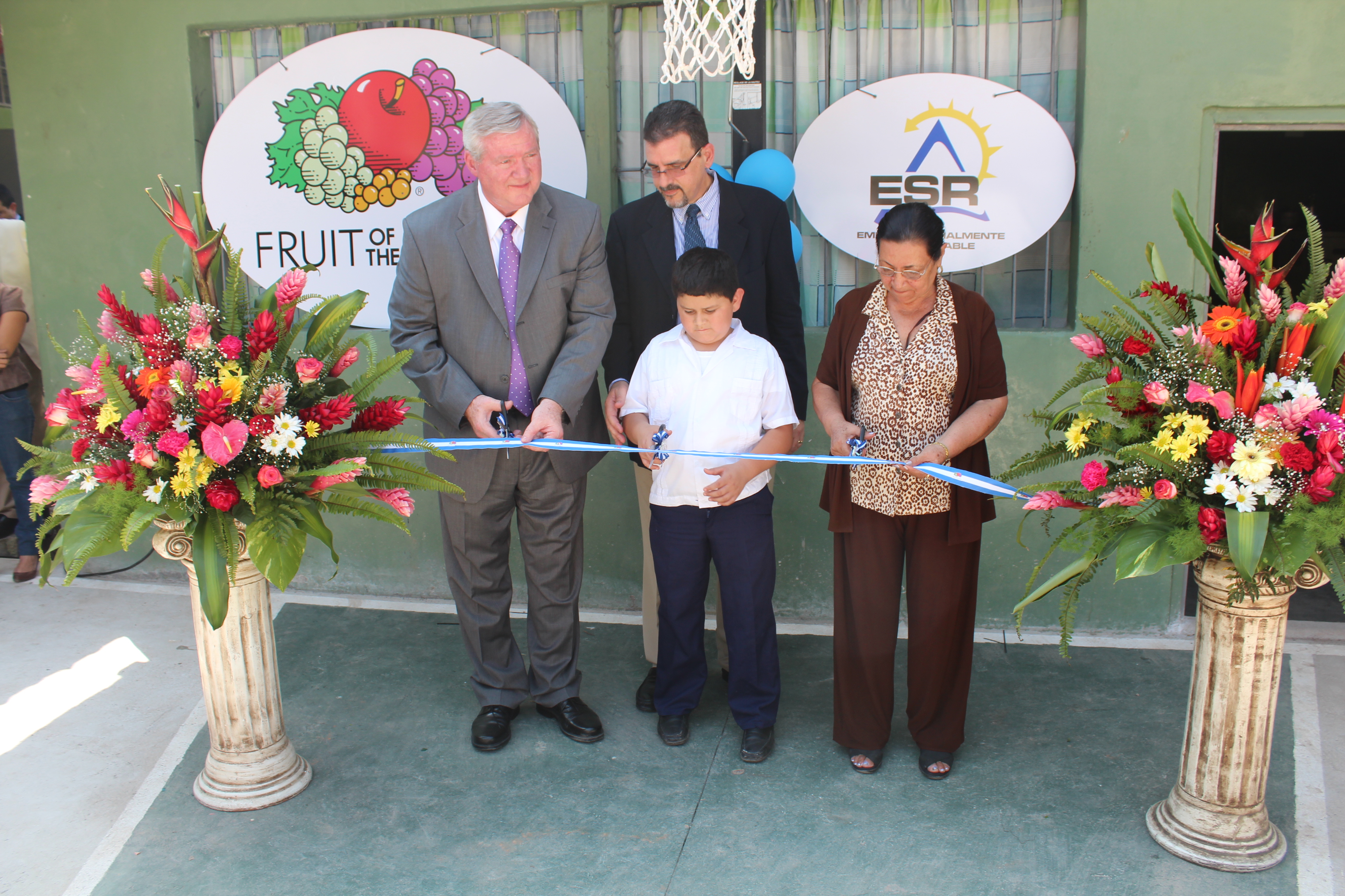 Representante de Fruit of The Loom, la directora de la escuela Genoveva Boquín y un alumno realizan el corte de la cinta inaugural.